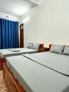 two beds in a room with blue curtains at Thành Đạt Hostel ( Hostel and Motobike Rental ) in Bản Tùy