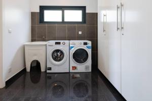 un lavadero con lavadora y lavadora en Luxury Haven: Heated Pool, AC & Sun, en Ponta do Sol