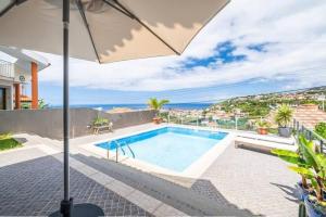 una villa con piscina y sombrilla en Luxury Haven: Heated Pool, AC & Sun, en Ponta do Sol