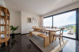 Un comedor con mesa y sillas y una gran ventana. en Luxury Haven: Heated Pool, AC & Sun, en Ponta do Sol