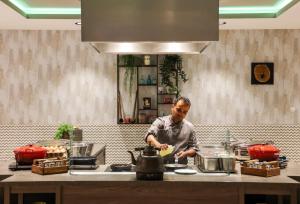 a man standing in a kitchen preparing food at Leonardo Royal Hotel Amsterdam in Amsterdam