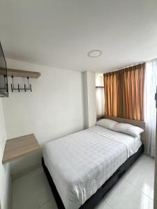 a small bedroom with a bed and a window at Hotel Adel in Manizales