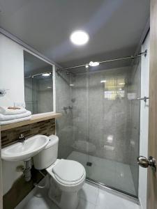 a bathroom with a shower and a toilet and a sink at Hotel Adel in Manizales