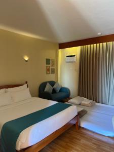 um quarto de hotel com uma cama e uma cadeira em Rufana Suites em Moalboal