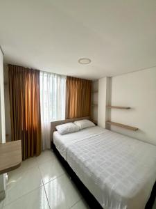 a bedroom with a large white bed in front of a window at Hotel Adel in Manizales