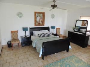 a bedroom with a bed and two chairs and a mirror at Woodgrange Garden Cottages in Hibberdene