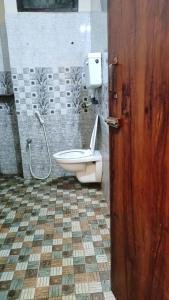 a bathroom with a toilet and a wooden door at L OCEAN GUEST HOUSE in Puducherry