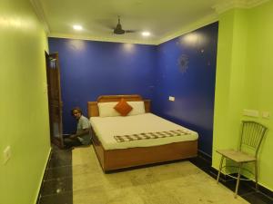 a man sitting in a bedroom with a bed in a room at L OCEAN GUEST HOUSE in Pondicherry