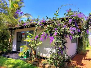 Una casa con flores púrpuras a un lado. en Hotel Water Nest en Etagama