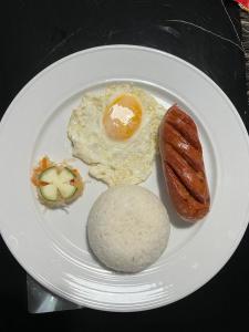 ein weißer Teller mit Ei, Wurst und Brot in der Unterkunft Arzel's Tiny House in Mangatarem