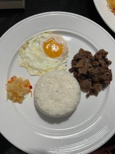 a white plate with an egg and other breakfast foods at Arzel's Tiny House in Mangatarem