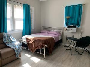 a bedroom with a bed with blue curtains and a couch at Chic Home Away From Home! in Bowling Green