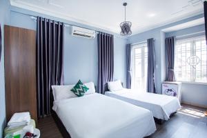two beds in a room with blue walls and windows at Mickey Homestay Hue in Hue