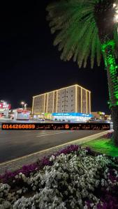 un bâtiment avec un palmier et un bâtiment avec des fleurs dans l'établissement رونزا للوحدات السكنية المفروشة Rwnza Hotel Apartments, à Tabuk
