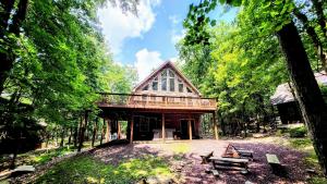 uma cabana no meio de uma floresta em Woodland Oasis by AvantStay Hot Tub Firepit Walk to Lake em Lake Harmony