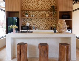 a kitchen with a counter with three wooden stools at Thom Farm and Retreat in Teurnoum