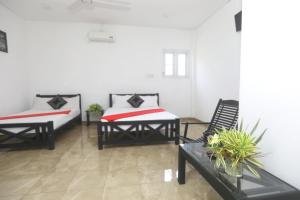 two beds in a room with two chairs and a couch at Hotel Water Nest in Etagama