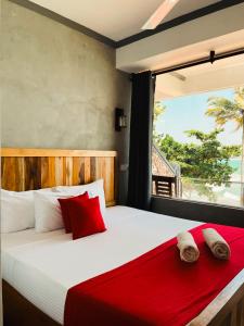 a bedroom with a bed with red pillows and a window at Coral Beach Hotel in Mirissa