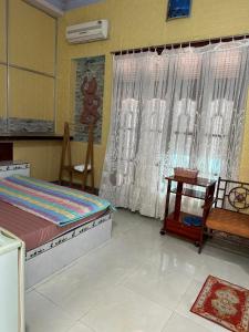 a bedroom with a bed and a table and a window at San Vuon Guesthouse in Mui Ne