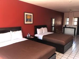 duas camas num quarto de hotel com paredes vermelhas em HOTEL BUGAMBILIAS em Ensenada
