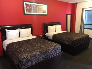 duas camas num quarto de hotel com paredes vermelhas em HOTEL BUGAMBILIAS em Ensenada