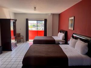 a hotel room with two beds and a red wall at HOTEL BUGAMBILIAS in Ensenada