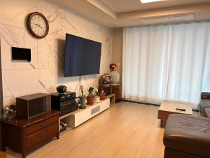een woonkamer met een flatscreen-tv aan de muur bij Byeollae Station ipark Suite in Namyangju