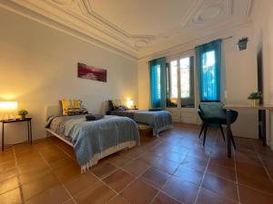 a bedroom with two beds and a table and windows at Arc De Triumph Rooms in Barcelona
