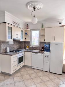 una cocina con armarios blancos y electrodomésticos blancos en Sunset beach club Fethiye 3 bedroom apartment, en Fethiye