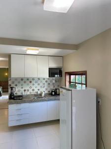 a kitchen with white cabinets and a refrigerator at Bangalô Villas do Pratagy in Maceió