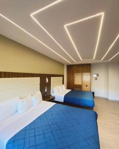 Habitación de hotel con 2 camas con sábanas azules en HOTEL BUGAMBILIAS en Ensenada