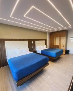 two beds in a hotel room with blue sheets at HOTEL BUGAMBILIAS in Ensenada