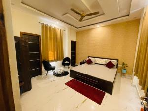 Atulyam Stays Sushant Golf City في لاكناو: غرفة نوم بسرير وكراسي في غرفة