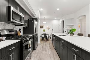 a kitchen with black cabinets and a sink and a stove at CozySuites Glendale by the stadium with pool 14 in Glendale
