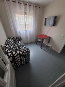 - un salon avec un lit et une table rouge dans l'établissement RAYMAR HOUSE, à Melilla