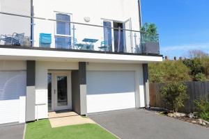 a white house with a garage and a balcony at Ty Jem in Criccieth