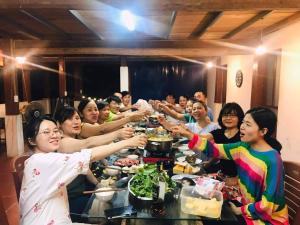 Ba Be Retreat house في Bak Kan: مجموعة من الناس يجلسون على طاولة يأكلون الطعام