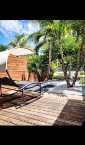 einen Stuhl und einen Regenschirm auf einer Holzterrasse in der Unterkunft Maison Casanova in Orient Bay