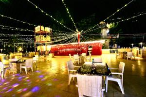 een restaurant met witte tafels, stoelen en verlichting bij Hotel Shiva Lake Mussoorie - 360 Degree View - Free Parking in Mussoorie
