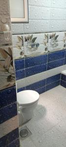 a bathroom with a toilet and a blue tiled wall at غرفه بشقه بأطلاله على البحر in ‘Izbat al Qaşr