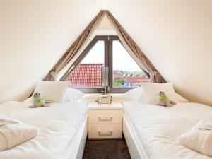 2 weiße Betten in einem Zimmer mit Fenster in der Unterkunft Reethuus Nord Modern retreat in Juist