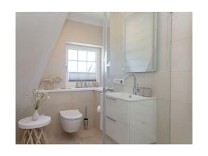 a white bathroom with a toilet and a sink at Rüm Hart II apartment 12 in Hörnum
