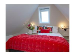 a bedroom with a red comforter on a bed at Rüm Hart II apartment 12 in Hörnum