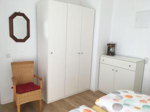 1 dormitorio con armarios blancos, silla y espejo en Sonnensteg Modern retreat en Juist