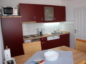cocina con armarios rojos y mesa de madera en Sonnensteg Modern retreat en Juist