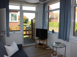 ein Wohnzimmer mit einem Sofa, einem TV und Fenstern in der Unterkunft Sonnensteg Modern retreat in Juist