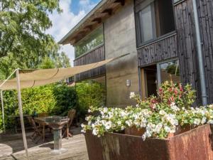 a house with a patio with flowers and an umbrella at House by the Park Modern retreat in Bispingen