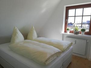 a bed with white sheets and pillows in a room at Rüm Hart II - Apartment 11 in Hörnum