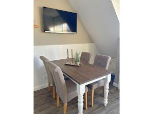 a dining room table with chairs and a tv on the wall at Rüm Hart II - Apartment 11 in Hörnum