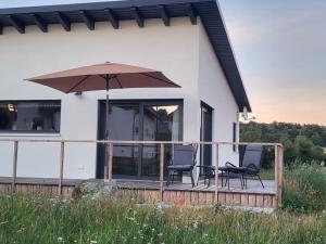 ein Haus mit zwei Stühlen und einem Sonnenschirm auf einer Terrasse in der Unterkunft Holiday home Birx Rhön in Birx